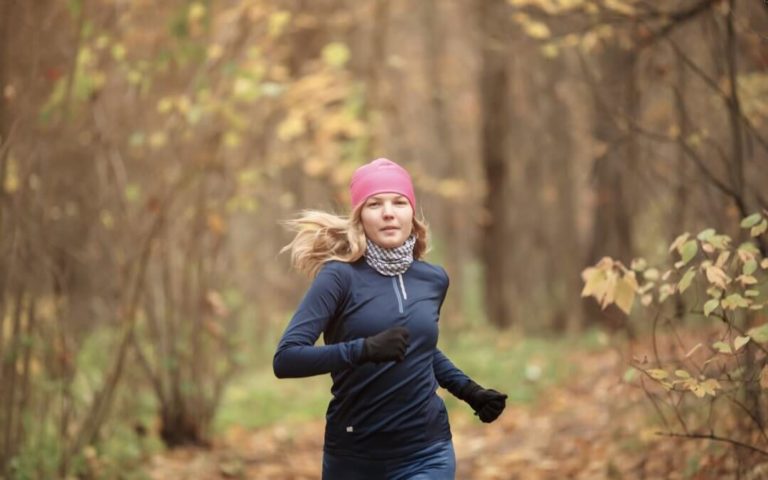 Billede af en kvinde i en efterårsskov der løber mod kameraet.