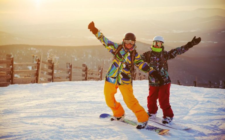 Billede af to personer der står på snowboard.